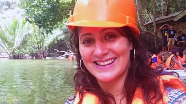 Autora sorrindo ao final do tour pelo Rio Subterrâneo, com vegetação tropical ao fundo.