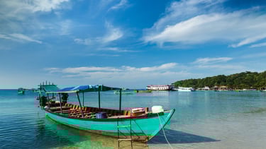 Barco de passeio ancorado na areia em Sihanoukville, pronto para levar visitantes às ilhas próximas.