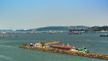 Chegada ao porto de Sihanoukville vista do navio, com barcos ancorados e a cidade ao fundo.