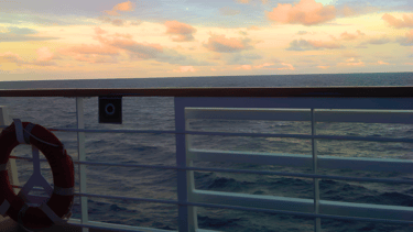 Vista do deck de navio de cruzeiro no mar ao entardecer rumo à Europa.