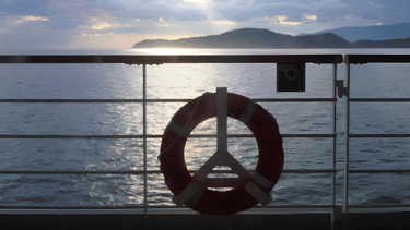 Navio de cruzeiro saindo do Rio de Janeiro, com montanhas ao fundo.