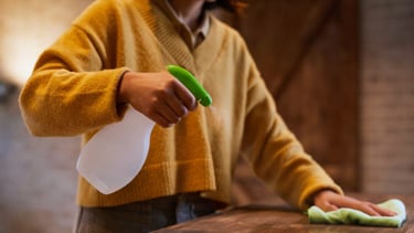 a woman is cleaning a table with a green cloth