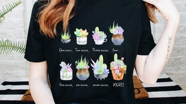 Girl wearing black succulent graphic tee with multiple illustrated succulent pots across the front.