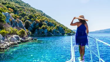 Woman on a boat tour enjoying the turquoise Mediterranean sea near the rocky coastline of Turkey.