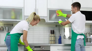 a man and woman cleaning a kitchen counter