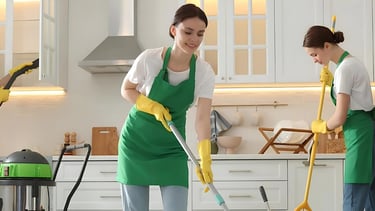 two women in aprons and aprons cleaning a kitchen