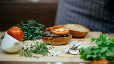 chef making a delicious burger with beef, tomato, mushrooms and onions.
