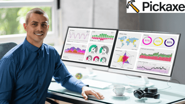 a man sitting at a desk with two monitors with data chart and graphs and a cup of coffee