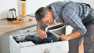 a man in a plaid shirt is fixing a dishwasher
