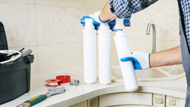 a man in a blue shirt is holding a water filterr