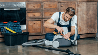 a man in overalls and overalls is cleaning a vacuum
