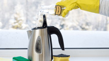 a person in a yellow glove is cleaning a kettle kettle
