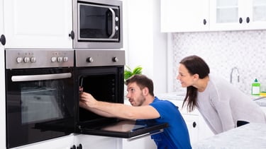 a man and woman are looking at a microwave