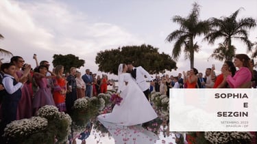 Beijo dos noivos em cerimônia ao ar livre em Brasília, rodeados por convidados e flores.