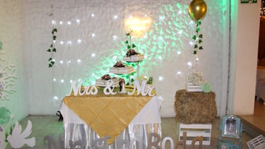 Mesa de boda decorada con pastel de varios niveles, luces y detalles dorados.