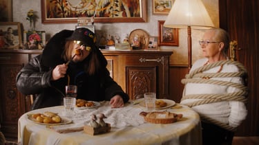 Lorenzo mange avec une vieille dame attachée par des cordes