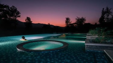 Person relaxing in a pool at Agraharam with serene surroundings.