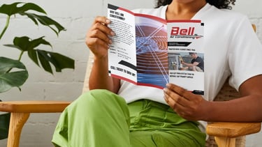 Bell Air customer reading a service agreement brochure while a routine HVAC maintenance inspection