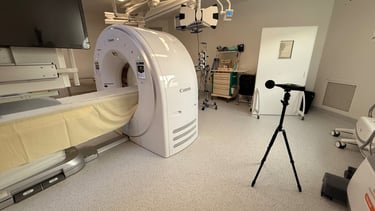 Un scanner CT Canon moderne dans une salle d'imagerie médicale lumineuse avec un sonomètre trépied.