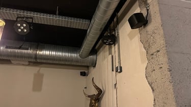 Plafond industriel avec conduits CVC exposés, éclairage de scène et décoration murale de crâne de t