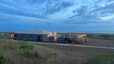 Bar de plage rustique et patio extérieur avec guirlandes lumineuses sur une plage de sable
