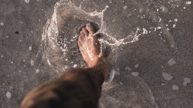 a person standing in the water with their feet in the water
