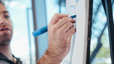 a man is writing on a white board