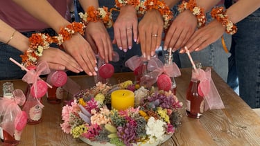 Bridal party wearing floral bracelets over a dried flower centerpiece with a yellow candle.