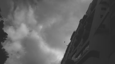 Edificio bajo un cielo tormentoso y nublado en blanco y negro.