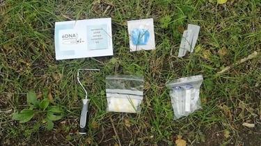 A terrestrial eDNA sample collection kit with roller, vials, and instructions laid out on grass.