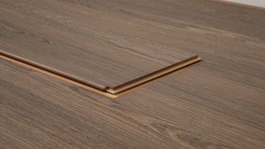 A close-up of premium wooden flooring installation in a high-end South Asian / Indian residence, showing the quality of joinery and the rich muted brown finish.