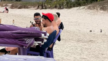 a man in a red hat and sunglasses on a beach
