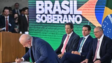 Lula assinando documentos em uma mesa, com Fernando Haddad e outros políticos observando.