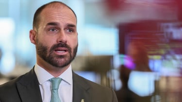  Eduardo Bolsonaro, com terno e barba, com uma expressão séria, em um close.