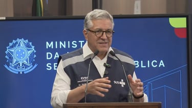 a man in a vest and glasses speaking into a microphone