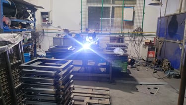 Professional welder welding metal frames in an industrial workshop with bright sparks and safety gear.