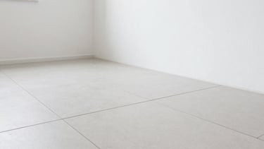 Close-up shot of perfectly aligned large format floor tiles meeting a clean, freshly painted wall corner in a renovated Verona apartment, natural light, sharp focus on the grout lines and precision