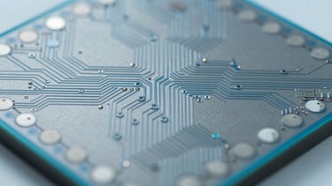 Extreme macro technical photography of a silicon wafer die, showing precise microscopic circuit pathways, bright fluorescent cleanroom lighting, cool gray and blue tones, sharp focus.