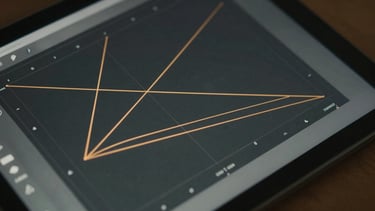 A close-up of a digital tablet screen showing geometric coordinate graphing with precise amber lines, 16:9 aspect ratio