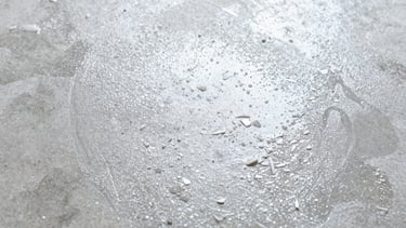 Close-up, top-down macro shot of fine epoxy flakes evenly distributed over a wet concrete surface, bright studio lighting, cool tones.