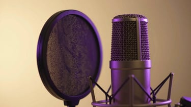 Close-up of a professional studio microphone with a soft purple glow on the pop filter, warm gold background lighting, shallow depth of field.