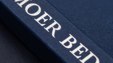 Macro photography of an elegant book spine with silver foil lettering against a dark blue background. Professional studio lighting.