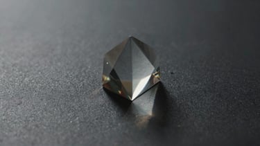 Moody close-up shot of light refracting through a glass prism onto a dark textured surface, soft natural shadows