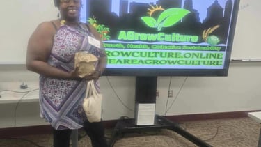 A woman stands by an AGrowCulture digital display promoting health and collective sustainability.