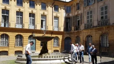 place avec une fontaine à Aix-en-Provence avec des personnes regardant l'architecture