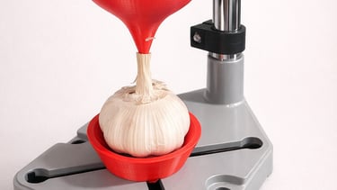 A whole garlic bulb held in a gray metal drill stand with 3D printed red plastic attachments.