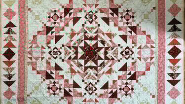 Traditional quilt featuring a central medallion surrounded by pieced borders.