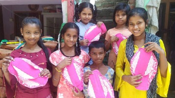 Six young girls holding up reusable sanitary napkins