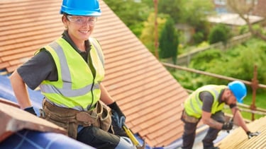 happy roofing worker smiling for the camera while the other installs