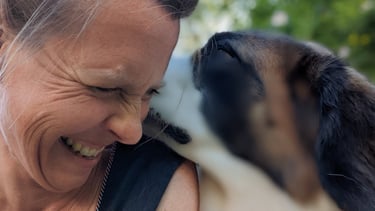 a woman is smiling and holding a dog